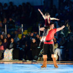 Child performer perched on partner's shoulder