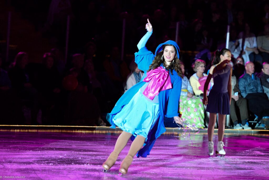 A woman in a blue dress on an ice rink.