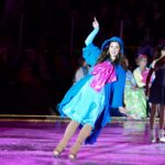A woman in a blue dress on an ice rink.
