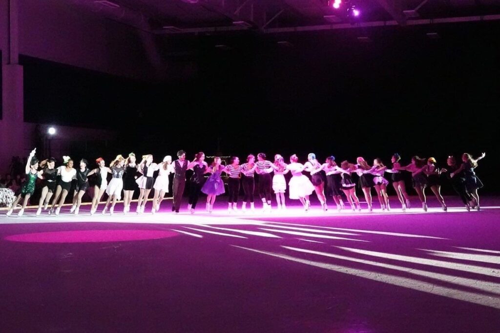 A close-up shot of the girls performing under lights on ice