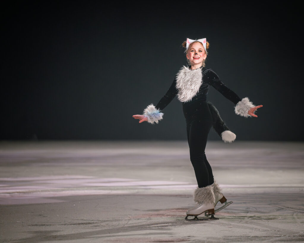 A young girl ice skating in a cat costume.