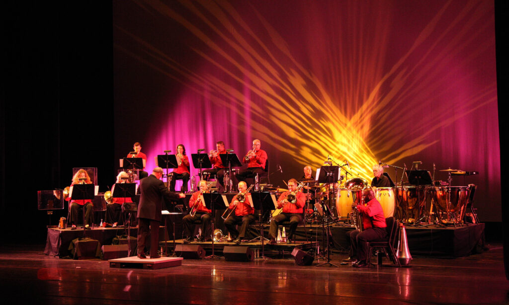 Orchestra performing on stage with colorful lighting.
